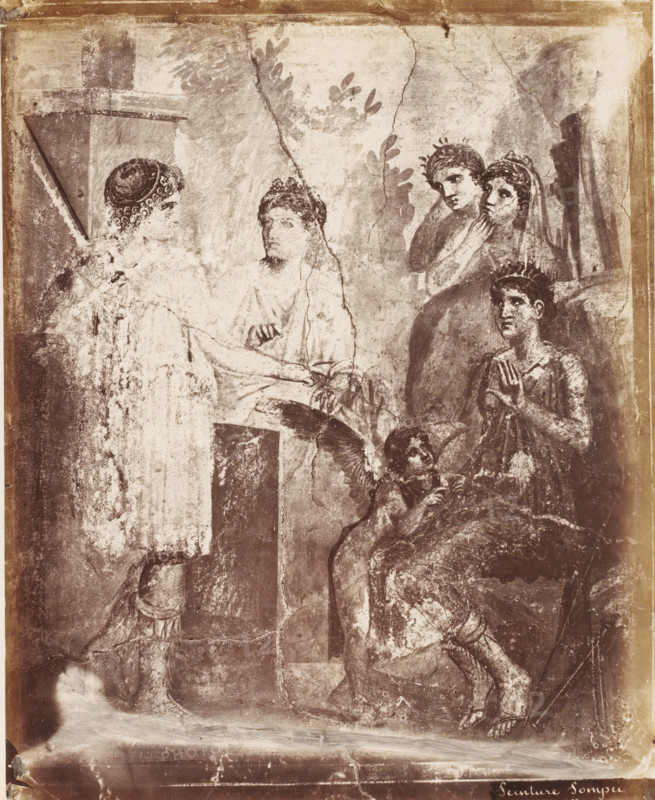 Photo reproduction of a fresco in Pompeii, Peinture Pompei, photograph, reproduction, number: '78.', number: '11', Pompeii, after painting by anonymous, 1851 - 1900, photographer, pasteboard, paper, albumen print, albumendruk, height 400 mm x width 304 mm, wall covering, A faded mural panel shows several figures in classical attire arranged in a scene set against a textured background with leafy motifs and architectural elements; on the left a standing figure faces a seated figure draped in robes, their hands extended toward each other, while to the right a group of three figures stands and sits, two of them wearing wreaths and one seated with hands raised in a gesture, a small winged childlike figure near the seated person looks upward, and at the bottom a partially visible figure kneels with legs bent and feet in sandals, all rendered in worn monochrome tones with visible cracks and areas of surface loss.