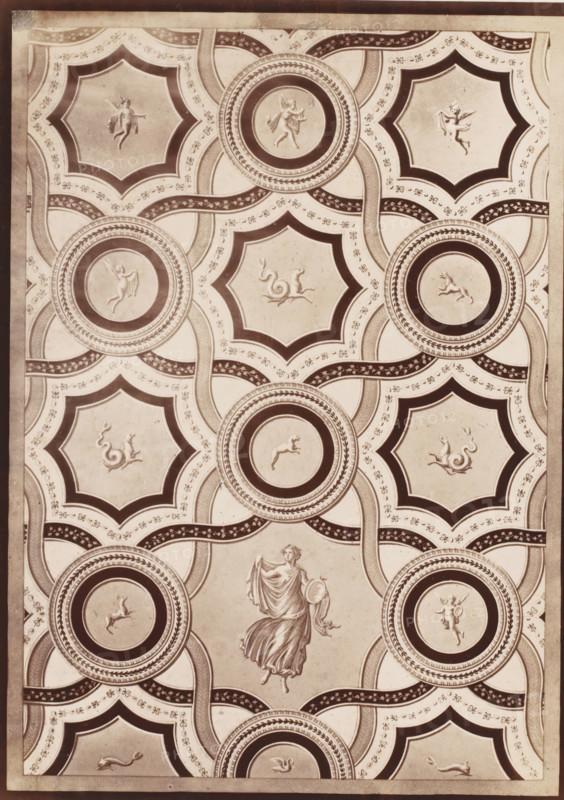 Photo reproduction of a ceiling painting, possibly in Pompeii, photograph, reproduction, number: '11', number: '28.', after painting by anonymous, 1851 - 1900, photographer, pasteboard, paper, albumen print, height 405 mm x width 307 mm, picture, painting, (decorated) ceiling, Pompeii, A rectangular panel with a repeating ornamental pattern of interlocking circular medallions and star-shaped frames, rendered in sepia tones; each circular medallion contains a raised relief figure of a small animal or cherubic figure in profile, surrounded by concentric decorative borders, while the star-shaped frames hold stylized mythical creatures and drapery-clad figures in various poses; ornate curved bands with leaf and floral motifs weave between the medallions and frames, creating a lattice across the surface; a larger draped female figure holding a round object appears near the center, depicted in a flowing garment with detailed folds; the panel is bordered by a narrow solid edge with subtle wea...