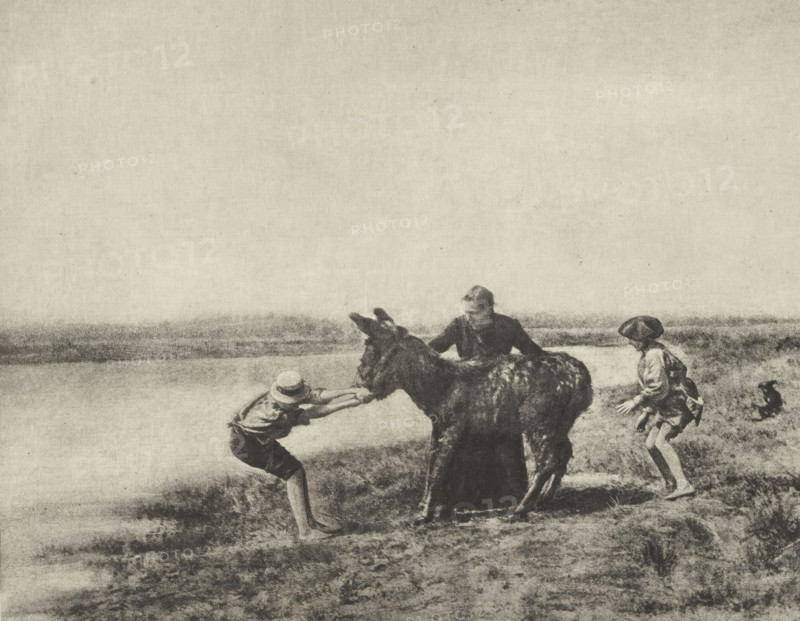 Obstination, Donkey refuses to walk, photomechanical print, photographer: J. Mantélier, cliché maker: Fillon & Heuse, printer (person): Charles Wittmann, Paris, c. 1891 - in or before 1896, printer (person), paper, photoaquatint, height 141 mm x width 176 mm, ass, donkey, man struggling with animals, A grainy monochrome scene showing a shoreline with low grasses and a calm body of water in the background, populated by three children and a donkey; one child stands on the left leaning forward and gripping the donkey’s head while wearing a hat and rolled trousers, a second child stands behind the donkey with hands on its back and wearing a darker outfit, and a third child stands to the right in a skirt and hat with hands raised slightly; the donkey faces left with a shaggy coat and lowered head, and the horizon and sky occupy the upper portion of the image.