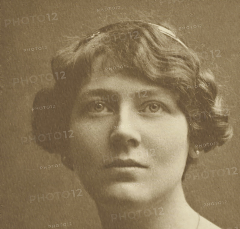 Portrait of an unknown woman, photograph, c. 1891 - c. 1896, photographer, paper, gelatin silver print, developed gelatin silver print, height 150 mm x width 156 mm, height 367 mm x width 274 mm, This photograph is not mentioned in the publication of the Troisième Exposition d'Art Photographique. It may have been added to the cover later., adult woman, historical persons not known by name - BB - woman, A sepia-toned close-up of the upper face and lower neck of a person with short wavy hair, visible eyes looking slightly upward, softly arched eyebrows, a straight nose, closed lips with a neutral expression, a rounded chin, a smooth neck, and a small earring visible at one ear, all against a plain background with a textured, aged appearance.