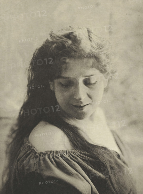 Portrait, Portrait of an unknown young woman, photomechanical print, photographer: Maurice Brémard, cliché maker: Fillon & Heuse, printer (person): Charles Wittmann, Paris, c. 1891 - in or before 1896, printer (person), paper, photoaquatint, height 222 mm x width 163 mm, historical persons not known by name - BB - woman, adolescent, young woman, maiden, A close-up portrait of a woman with long dark hair draped over one shoulder, her head tilted downward and eyes closed, wearing an off-the-shoulder blouse with gathered fabric and visible folds; the image has a soft, grainy texture and muted tones, with a blurred, neutral background.
