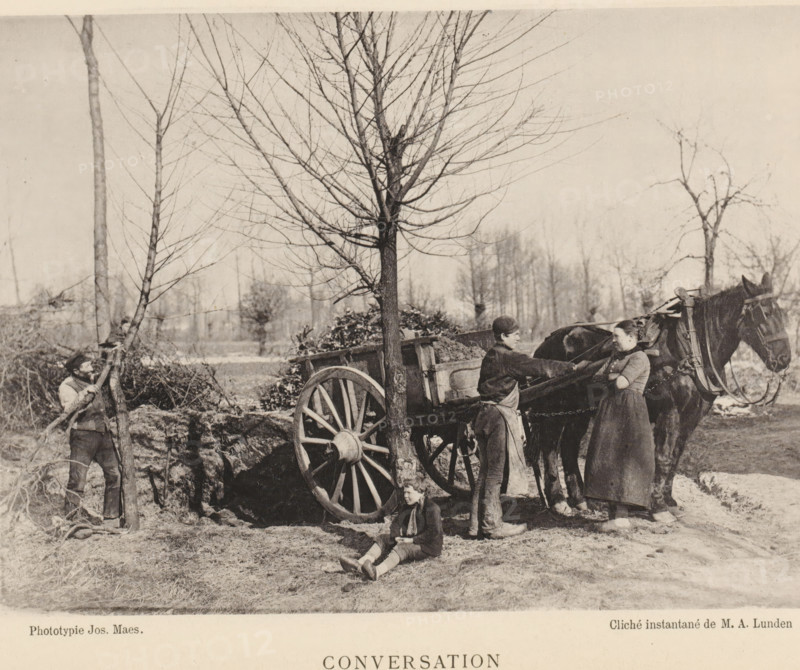 Conversation, People talking near a horse-and-cart, page, photomechanical print, inscription: 'Section d'Anvers - Exposition de 1889', photographer: Albéric Lunden, cliché maker: Joseph Maes, printer (person): Joseph Maes, Antwerp, c. 1883 - in or before 1888, Albéric Lunden, Joseph Maes, photographer, cliché maker, printer (person), paper, collotype, photoprint, height 115 mm x width 157 mm, Print on unnumbered page., conversation, dialogue, conversation piece, two-wheeled vehicle drawn by one animal, A sepia-toned outdoor scene showing a wooden cart with a large spoked wheel hitched to a dark horse, three adults and a child positioned around the cart, one person seated on the ground in front of the wheel, another standing beside the horse with arms crossed, a third person standing on the cart reaching toward the standing person, and a fourth person at the left holding a tree trunk; leafless trees fill the background and bare ground with patches of grass is visible underfoot.