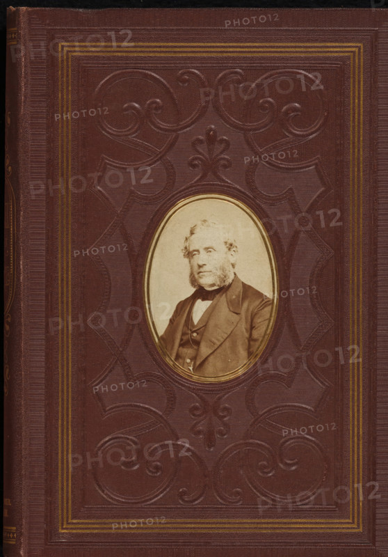 Portrait of Johannes Petrus Hasebroek, photograph, page, c. 1863 - in or before 1868, photographer, paper, albumen print, height 68 mm x width 48 mm, Photo on front cover., Person, Johannes Petrus Hasebroek, historical persons, A textured brown cover with an embossed decorative pattern and concentric rectangular borders in a lighter tone, featuring an oval inset with a sepia portrait of a bearded man wearing a jacket and bow tie, the portrait surrounded by a thin gilded rim.