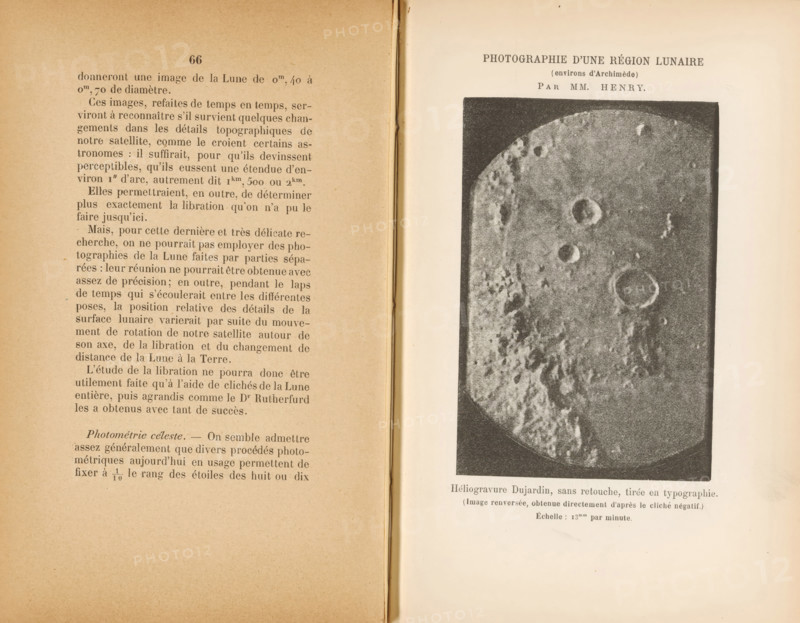 View of the moon with the Archimedes on the right of the center, Photographie d'une région lunaire, environs d'Archimède, page, photomechanical print, photographer: Henry Frères, cliché maker: Paul Dujardin, c. 1882 - in or before 1887, paper, photoaquatint, height 100 mm x width 67 mm, surface of the moon, Archimedes, An open book spread with a left page filled with printed paragraphs of small dark text on aged beige paper and a right page showing a large dark rectangular photographic plate of a textured round surface resembling a cratered moon, the photograph bordered by a white margin and positioned toward the top of the page, with a narrow gap between the two pages revealing the book spine and slightly darker inner binding.