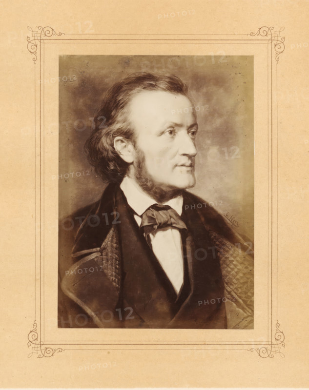 Photo reproduction of a painted portrait of Richard Wagner by Carl Jaeger, photograph, reproduction, page, after painting by Carl Jaeger, in or after 1870 - in or before 1872, photographer, paper, albumen print, albumendruk, height 150 mm x width 107 mm, Person, Richard Wagner, picture, painting, portrait of composer, A sepia-toned portrait of a man shown in profile facing right, with wavy hair brushed back and sideburns, wearing a dark coat over a white shirt and a tied neckcloth, set against a mottled background and surrounded by a decorative rectangular border on aged paper.