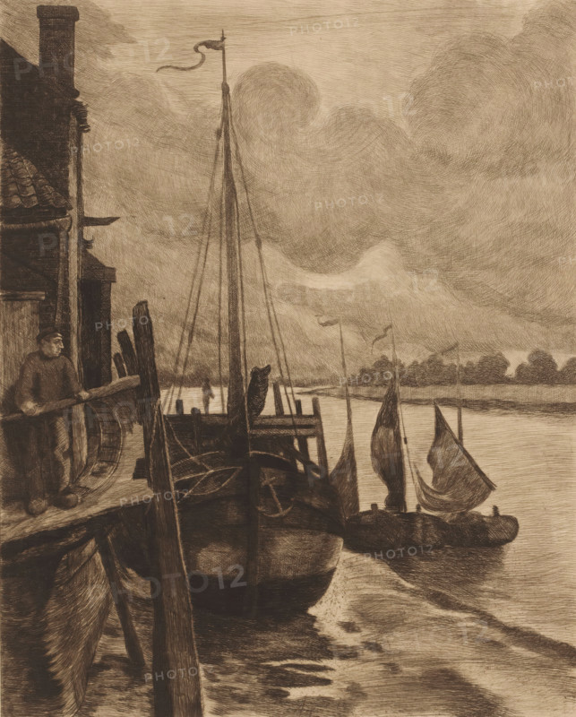 View of boats in the Scheldt near Rupelmonde, print, inscription: '1er Etat KM', printmaker: Karl Meunier, 1874 - 1894, paper, etching, drypoint, intaglio printmaking technique, drypoint and plate tone, height 325 mm x width 267 mm, sailing-ship, sailing-boat, landscapes with waters, waterscapes, seascapes (in the temperate zone), Scheldt, Rupelmonde, A sepia-toned scene of a riverside with several moored sailboats, their masts and furled sails rising against a cloudy sky, a larger boat in the foreground tied to a wooden dock with a coiled rope and anchor visible on its deck, a man standing on the dock near a building with a tiled roof and chimney holding a plank, wooden posts and beams forming the dock structure, distant low tree-lined shore across the water, and swirling textured clouds filling much of the upper area.