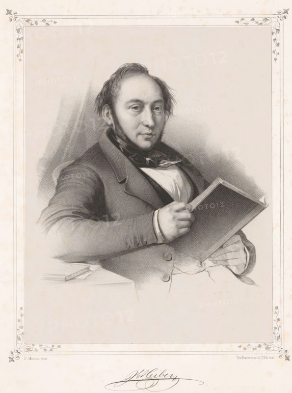 Portrait of Johan Ludvig Heiberg, print, inscription: 'JLHeiberg', inscription: 'D. Monies pinx.', inscription: 'Em. Baerentzen & Co lith.Inst.', printmaker: Emilius Ditlev Baerentzen, printer (person): Baerentzen & Co., Em., Copenhagen (city), after painting by David Monies, in or after 1837 - in or before 1868, printer (person), paper, chine collé, lithography, lithography on chine collé, height 357 mm x width 274 mm, height 226 mm x width 178 mm, Person, Johan Ludvig Heiberg, historical persons, A seated man with short hair and sideburns faces forward while holding an open book, wearing a dark coat over a shirt and cravat, his left arm resting on a surface beside a closed writing implement, rendered in a detailed pencil or charcoal portrait framed by a decorative border on aged paper.