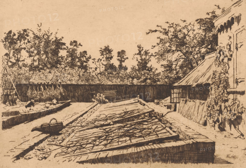 Greenhouse frames, Ewijkshoeve (original title), Vegetable garden at Ewijkshoeve, print, printmaker: Willem Bastiaan Tholen, 1870 - 1931, paper, etching, drypoint, intaglio printmaking technique, height 179 mm x width 260 mm, garden, backyard, vegetables, Den Dolder, A sepia-toned ink drawing showing a riverside scene with a long narrow boat in the water near the left edge, two figures seated in the boat wearing hats, a low wooden dock or platform extending into the foreground with stacked planks and scattered twigs, a small woven basket or bag on the ground near the water, a dark wooden fence running across the middle distance, dense trees and foliage rising behind the fence, a building with a sloped roof and a latticed window on the right, climbing plants along the building's wall, and a clear pale sky above.