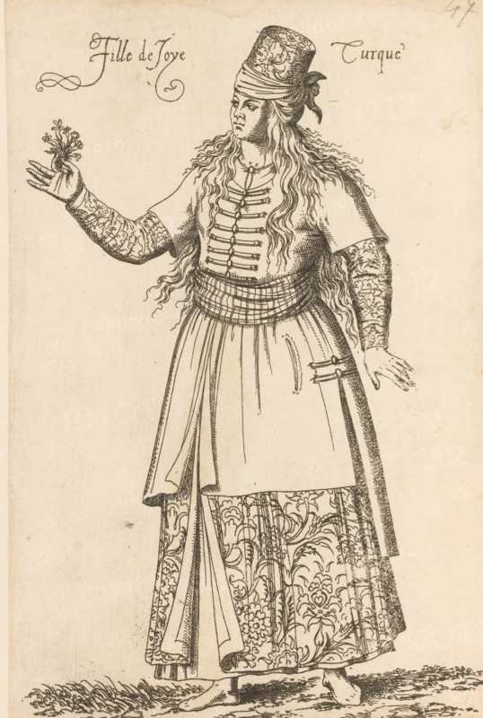 Prostitute from Turkey, Fille de Joye Turque, print, album page, book illustration, Print is part of an album., printmaker: Léon Davent, after drawing by Luca Penni (attributed to), after drawing by Nicolas de Nicolay (possibly), publisher: Guillaume Rouille (I), Lyon, 1555 - 1568, Léon Davet, Attributed to, paper, etching, mounted on album page, height 254 mm x width 169 mm, A tall figure wearing a patterned cylindrical hat and long wavy hair stands with one arm extended holding a small leafy sprig and the other arm relaxed at the side; the figure wears a short-sleeved top with decorative fastenings down the front, long ornate sleeves with floral motifs, a wide wrapped sash at the waist, and a long skirt with large floral patterns and draped panels, and the feet are bare standing on textured ground.