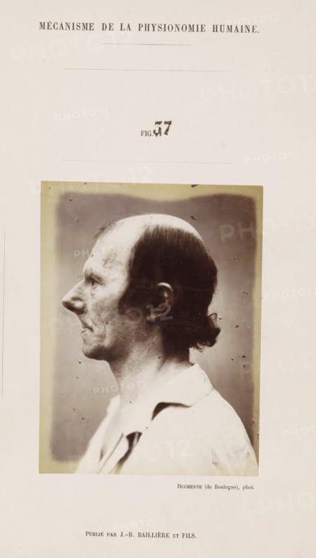Portrait of a subject: 'un vieillard', photograph, page, Unnumbered page with photo 37 from Mécanisme de la physionomie humaine ou analyze électro-physiologique de l'expression des passions (Atlas)., photographer: Guillaume Benjamin Amand Duchenne, France, publisher: JB Baillière et Fils, Paris, c. 1860 - in or before 1862, Guillaume Benjamin Amand Duchenne, JB Baillière et Fils, photographer, publisher, paper, albumen print, albumendruk, height 119 mm x width 89 mm, experiment, test, science and technology, old man, face, morphology of facial expression, physiology and anatomy, physiognomy, nervous system, neurology, A sepia-toned portrait photograph of an older man shown in profile facing left, with a receding hairline and short dark hair at the back tied into a small knot, visible wrinkles and textured skin on his face and neck, a prominent nose and thin lips, wearing a light-colored collared garment, the rectangular photograph is mounted on a light page with a faint darker rectangu...
