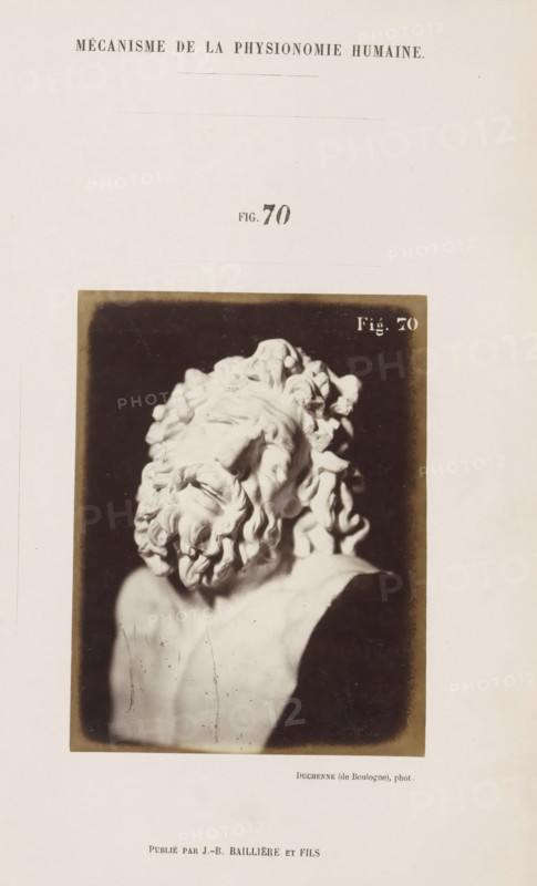 Image of 'Laocoon de Rome', photograph, page, Unnumbered page with photo 70 from Mécanisme de la physionomie humaine ou analyze électro-physiologique de l'expression des passions (Atlas)., photographer: Guillaume Benjamin Amand Duchenne, France, publisher: JB Baillière et Fils, Paris, c. 1860 - in or before 1862, Guillaume Benjamin Amand Duchenne, JB Baillière et Fils, photographer, publisher, paper, albumen print, albumendruk, height 118 mm x width 92 mm, piece of sculpture, reproduction of a piece of sculpture, experiment, test, science and technology, face, morphology of facial expression, physiology and anatomy, physiognomy, nervous system, neurology, A sepia-toned photograph of a sculpted bust showing a head tilted back and turned to the side, with deeply carved curly hair and a full curled beard, set against a dark rectangular background framed by a lighter border, mounted on a pale page.