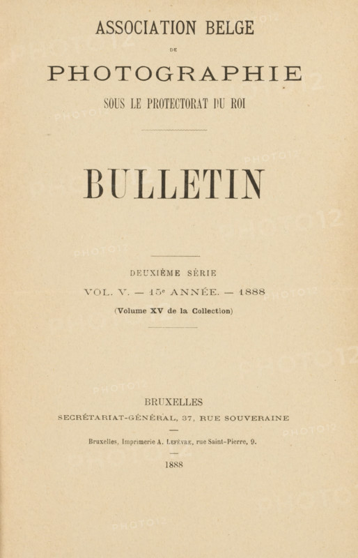 Association belge de photographie bulletin 15e année: 1888, book, printer (person): A. Lefèvre, Brussels, printer (person), pasteboard, biological material, paper, blotting paper, leather, marbled paper, baryta paper, letterpress printing, agate marbled paper, collotype, Woodburytype, heliotype, chlorobromide development paper print, autotype, height 243 mm x width 172 mm x thickness 49 mm, A vertically oriented aged paper page with a centered large bold heading near the top, additional smaller lines of printed headings and decorative lines arranged vertically down the page, a wide blank margin surrounding the printed area, and a visible horizontal fold across the lower third of the page.