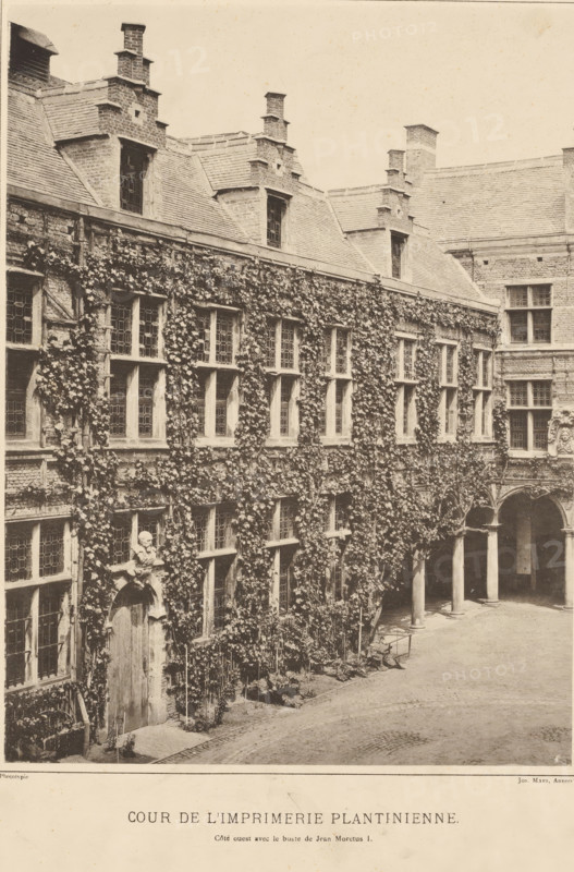 Courtyard of the Plantijn printing house in Antwerp, Cour de l'imprimerie plantinienne, Views of the Plantijn printing house, photomechanical print, View of the courtyard of the Plantijn printing house. West facade with bust of Jean Moretus I., maker: Joseph Maes, 1848 - 1908, Joseph Maes, paper, collotype, photogravure, height 445 mm x width 310 mm, The Plantijn printing house was the printing house and residence of the Plantin-Moretus publishing family, currently the Plantin-Moretus Museum., printing, printing office, Antwerp, A sepia photograph of a courtyard facade of an old stone building covered in climbing ivy, showing multiple tall rectangular windows with small panes set in stone frames and a row of dormer windows set into a steep tiled roof with ornate brick chimneys; the ground level features an arched doorway topped by a sculpted bust, a covered arcade with stone columns and arches, and a paved courtyard area in front, with tendrils of ivy and scattered low plants along the...