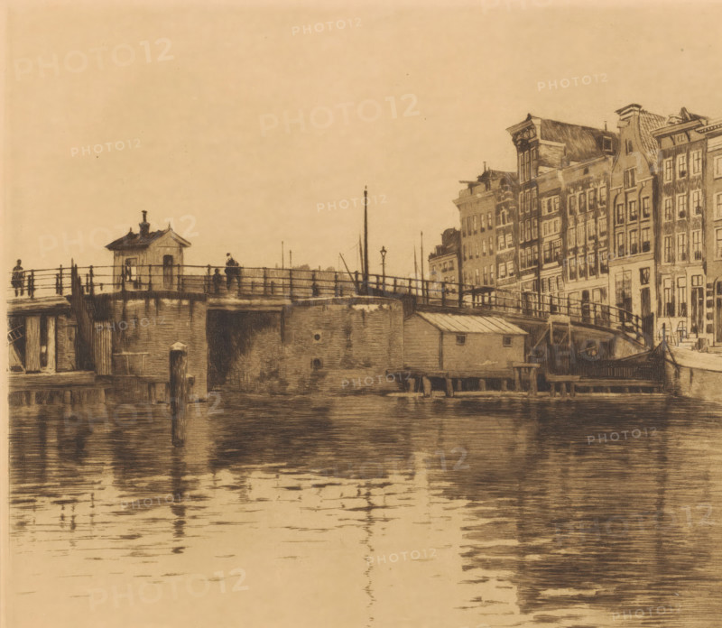 View of the Waalseilandsgracht towards the Kraansluis, Kraansluis, houses on the right (original title), print, annotation: 'second state', printmaker: Willem Witsen (signed by artist), c. 1911 - c. 1912, paper, etching, aquatint, height 279 mm x width 318 mm, urban housing, bridge in city across river, canal, Amsterdam, A sepia-toned scene showing a waterfront with a bridge and a row of narrow, multi-story buildings along the right edge, the buildings featuring tall windows and varied rooflines; the bridge has railings, a small hut-like structure, lamp posts, and a few silhouetted figures standing on it; wooden pilings and a low waterside building sit at the base of the bridge, and the water in the foreground reflects the bridge and buildings with horizontal rippling marks.