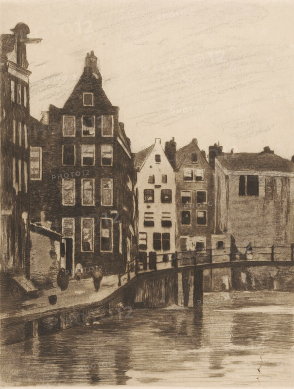View of houses and a bridge in Amsterdam, print, printmaker: Willem Witsen, Amsterdam, c. 1915 - c. 1919, inorganic material, paper, chalk, etching, aquatint, intaglio printmaking technique, aquatint and plate tone worked with black chalk, height 236 mm x width 186 mm, urban housing, canals, waters (in city), bridge, A sepia-toned etching shows a row of tall narrow buildings with steep gabled roofs lining a canal, their facades detailed with many rectangular windows and varying rooflines; a bridge crosses the canal in the foreground with railings and reflections in the water below, and a few small human figures appear on the street near a building entrance and on the bridge, while the sky above is lightly shaded.