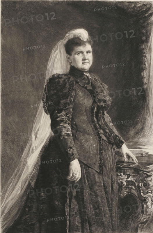 Portrait of Queen Emma, print, printmaker: Pieter de Josselin de Jong, 1890 - 1906, paper, chine collé, etching, intaglio printmaking technique, height 679 mm x width 423 mm, Person, Emma (Queen consort of the Netherlands), historical persons - BB - woman, A monochrome portrait of a woman standing with a long veil draped over her hair and shoulder, wearing a high-collared, long-sleeved dress with puffed upper sleeves and a fitted bodice decorated with small dots and lace trim, one hand resting on an ornately carved piece of furniture and the other hanging by her side, her hair swept up and a brooch at her throat, set against a dark, shaded background.