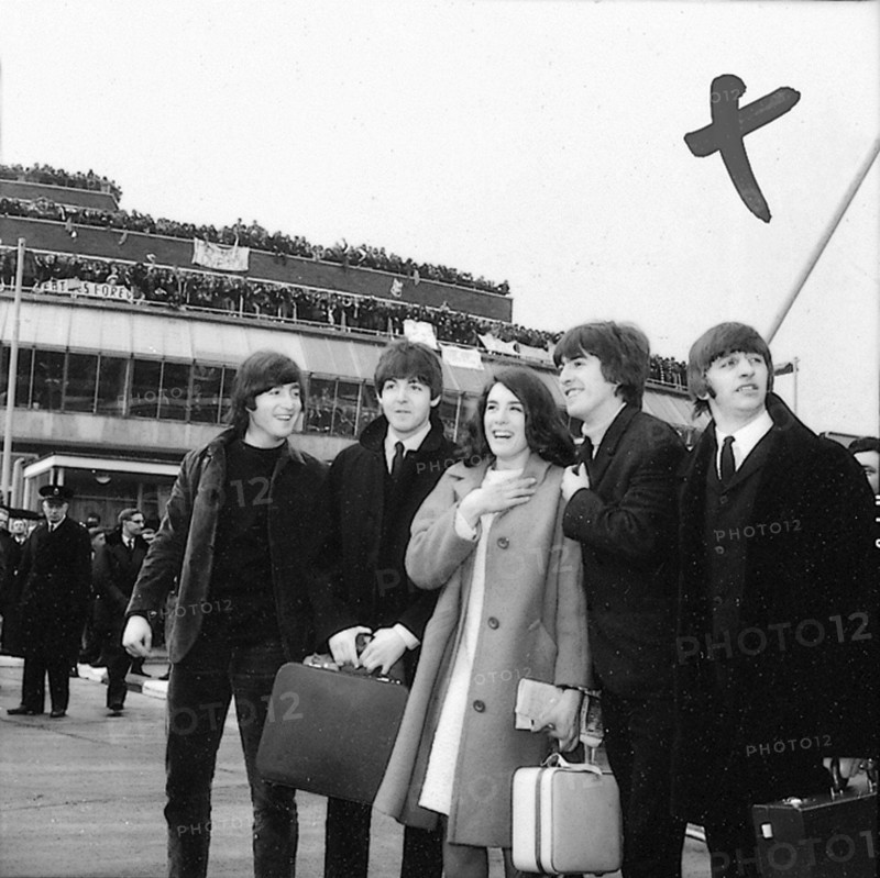 The Beatles leave London Airport bound for the Bahamas to commence filming on their second movie, "Help!", 22 February 1965. Lefto right:John Lennon, Paul McCartney, George Harrison and Ringo Starr.   With them is co-star, Eleanor Bron.