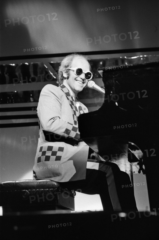 Elton John performing on stage, during the Elton John and Ray Cooper concert tours. Rainbow Theatre, London. 2nd May 1977.