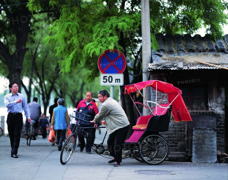 A man earns his living with the traditional pedicab by a hutong of Beijing,China