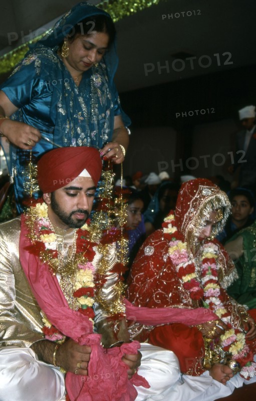 A mother garlands the groom for his wedding, India