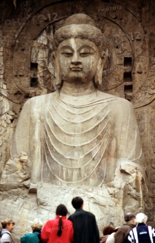 Touristes devant la statue géante de Bouddha dans les grottes bouddhiques de Longmen, à Luoyang, Chine