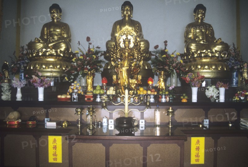 Chinese temple altar with row of Buddhas and kannon (female) with offerings