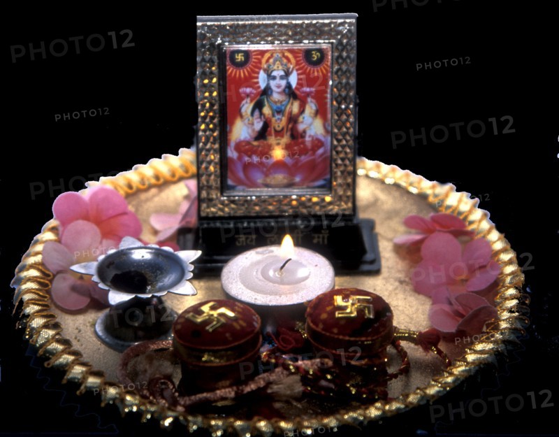 Puja tray with candle flowers and picture of Lakshmi