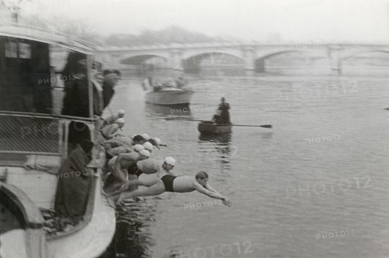 A series of swimmers is diving from a boat
