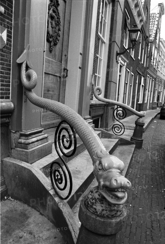Rampe ornementale à volutes en fer forgé, dont l'extrémité est sculptée, devant une façade. Enkhuizen, Pays-Bas.
2000