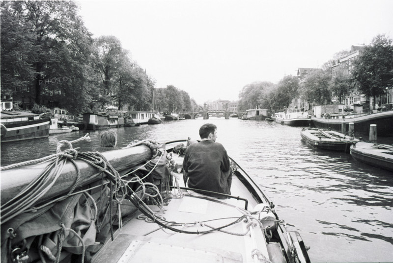 Canal d'Amsterdam vu depuis l'avant d'un bateau, une personne assise à la proue. Amsterdam, Pays-Bas.
2000