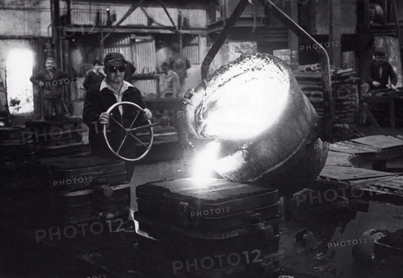 Worker handling a ladle of molten metal in an iron foundry. Tonge & Taggart, Dublin, Ireland.
1980