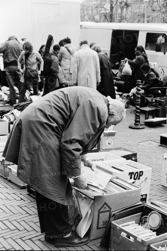 Homme penché sur des cartons, fouillant parmi les marchandises d'un étal, au milieu de la foule d'un marché. Amsterdam, Pays-Bas.
2000