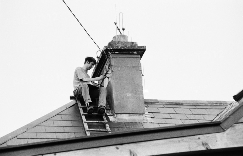Worker painting a chimney on a roof, using a ladder. County Mayo, Ireland.
2000