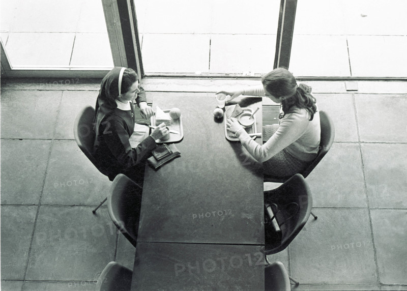 Deux jeunes femmes déjeunant face à face à une table de la cantine, vues en plongée. University College Dublin, Irlande.
1984