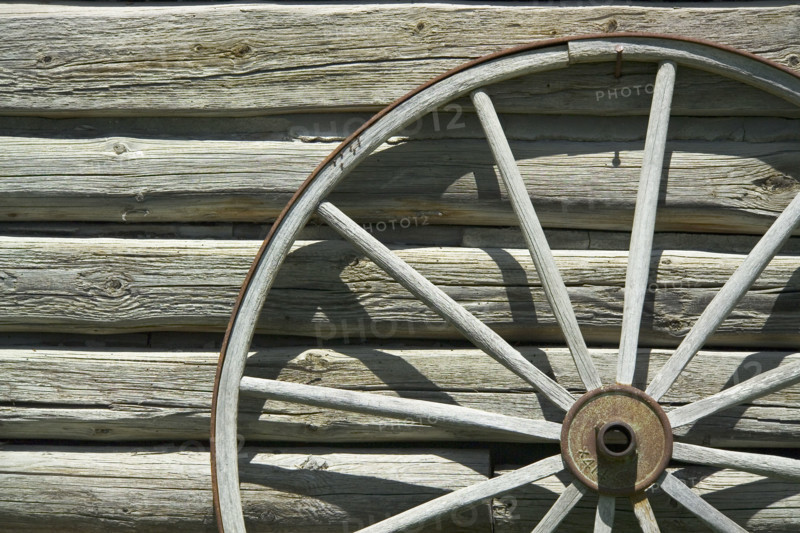 Wagon wheel against wooden wall.
