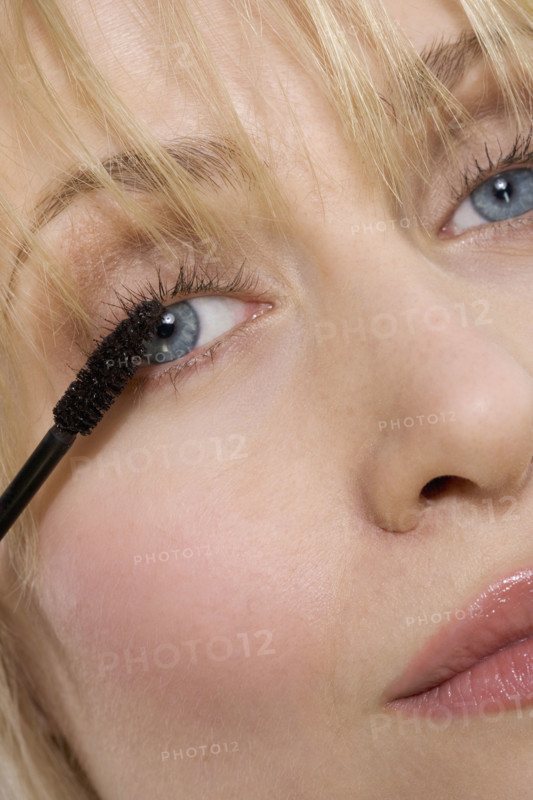 Woman's face with mascara brush.