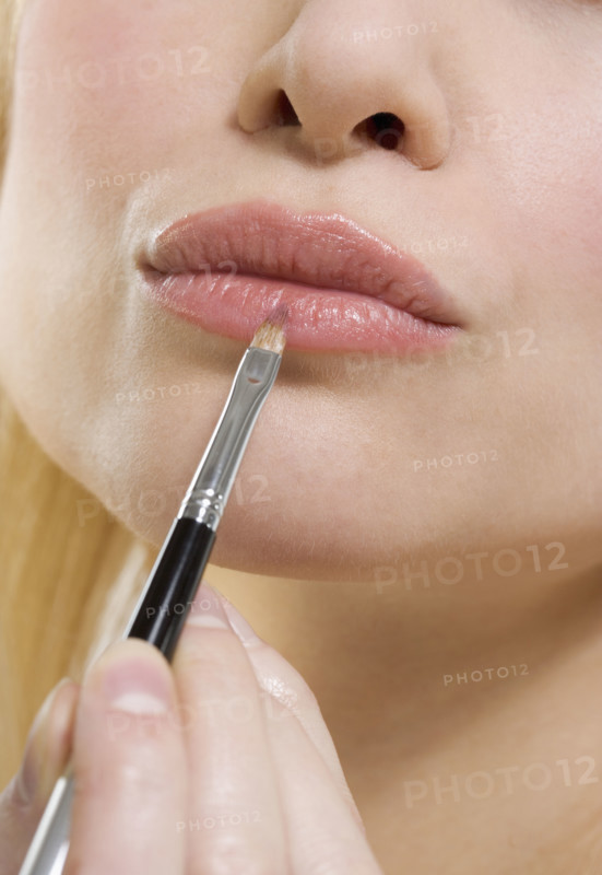 Woman's lips with lipstick brush.
