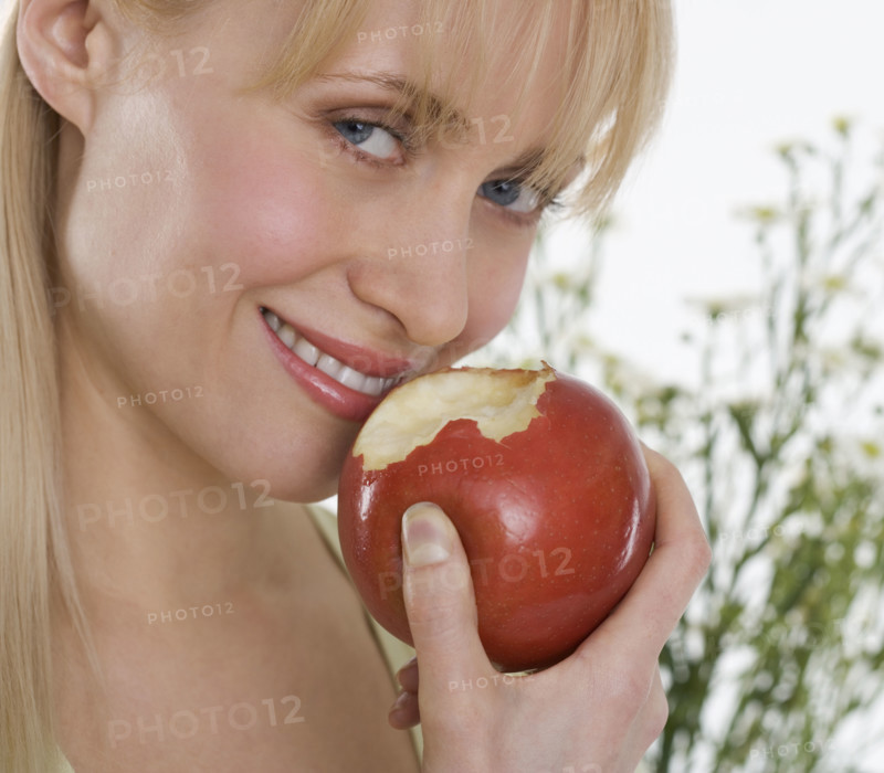 Smiling woman eating apple.