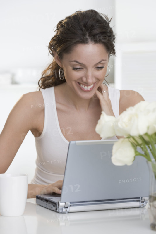 Smiling woman with laptop and cup.