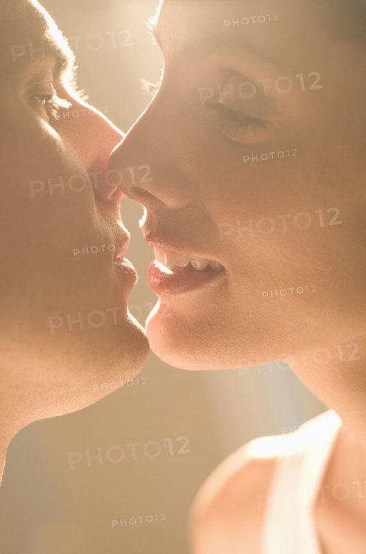 Closeup of couple kissing in sunlight.