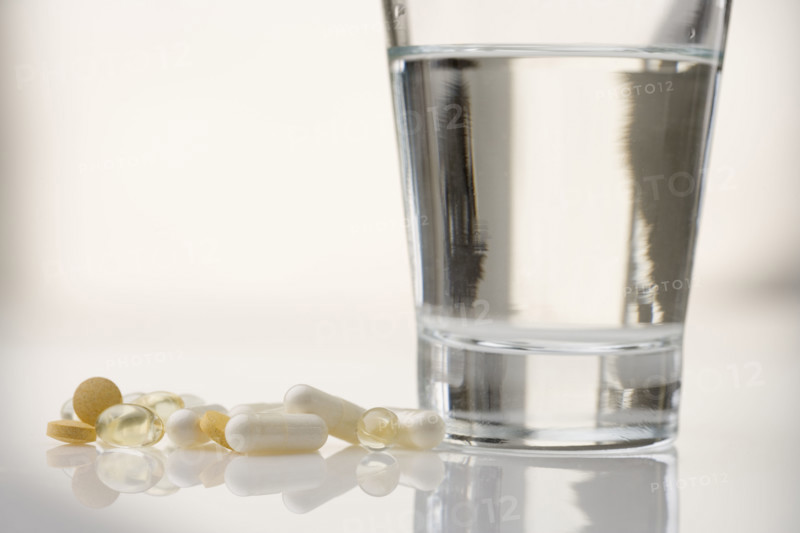 Pile of pills with water glass.