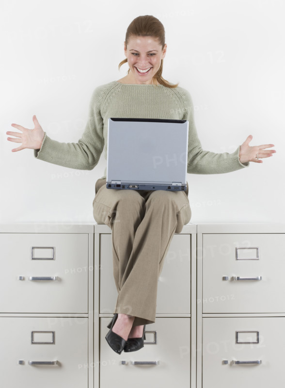 Woman with laptop atop file cabinets.