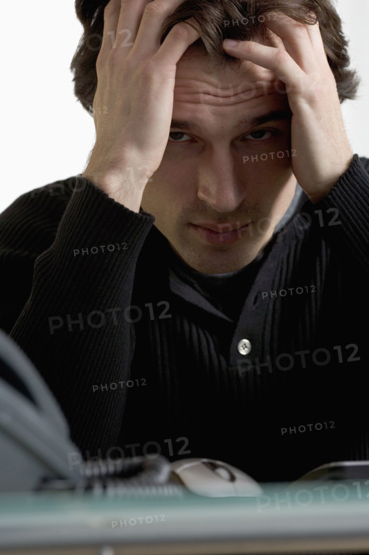 Closeup of upset man at desk.