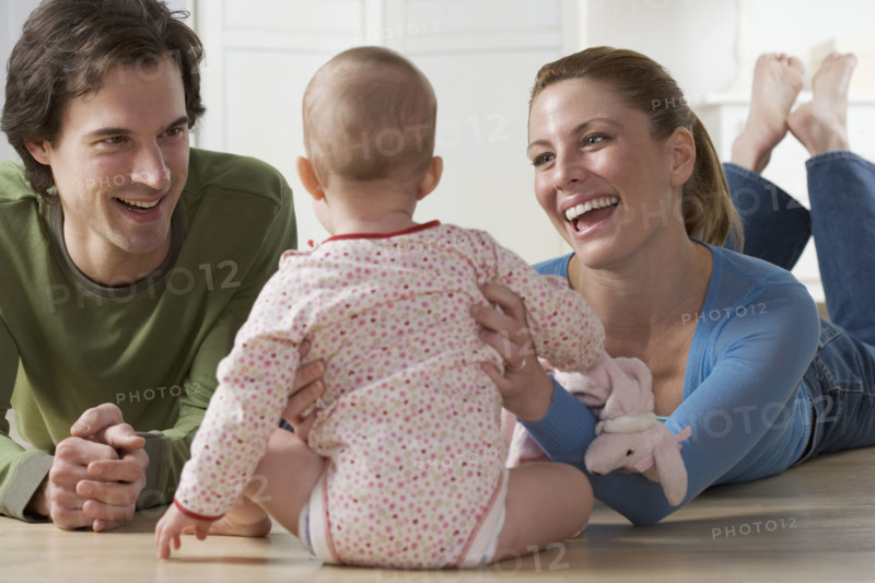 Couple playing with baby on floor.
