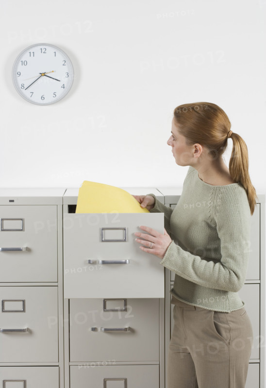 Woman with files looking at clock.