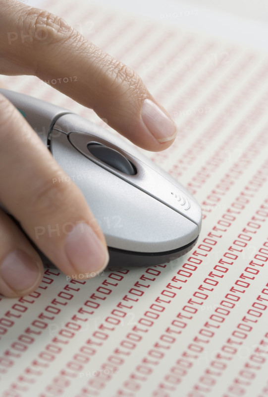 Hand on mouse with computer code.