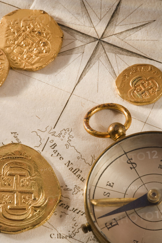 Still life of pieces of gold map and compass.