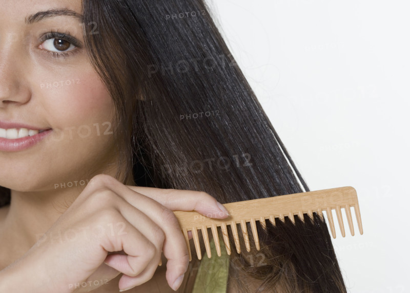 Woman combing hair with wooden comb.