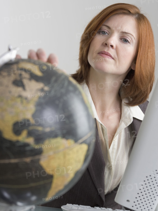 Woman at computer looking at globe.