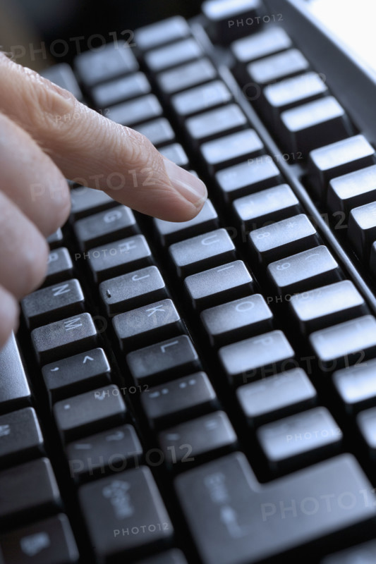 Closeup of finger and computer keyboard.